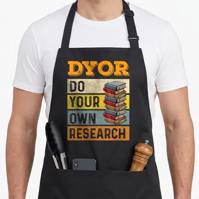 Tablier de cuisine noir avec inscription DYOR Do Your Own Research et illustration de livres colorés superposés.