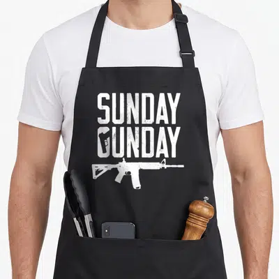 Tablier de cuisine noir avec l'inscription Sunday Gunday et un fusil AR15 en blanc délavé sur le devant.