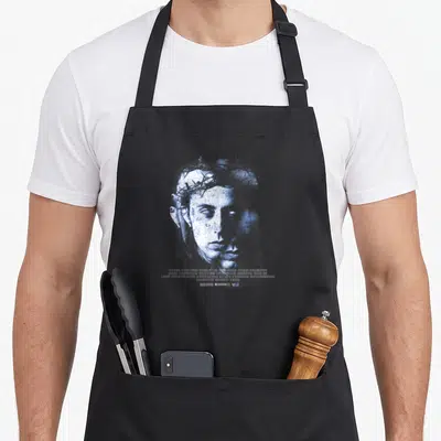 Tablier de cuisine noir avec portrait bleu stylisé portant une couronne d'épines et texte blanc en bas.