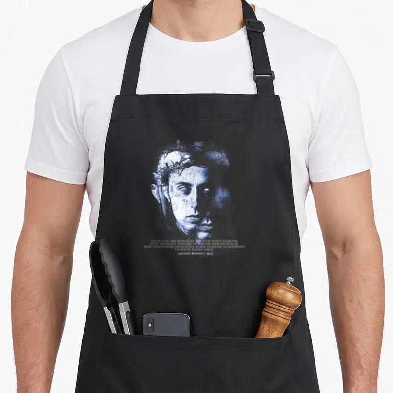 Tablier de cuisine noir avec portrait bleu stylisé portant une couronne d'épines et texte blanc en bas.