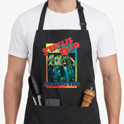 Tablier de cuisine noir avec illustration Status Quo Piledriver montrant des guitaristes aux longs cheveux sous un cadre multicolore.