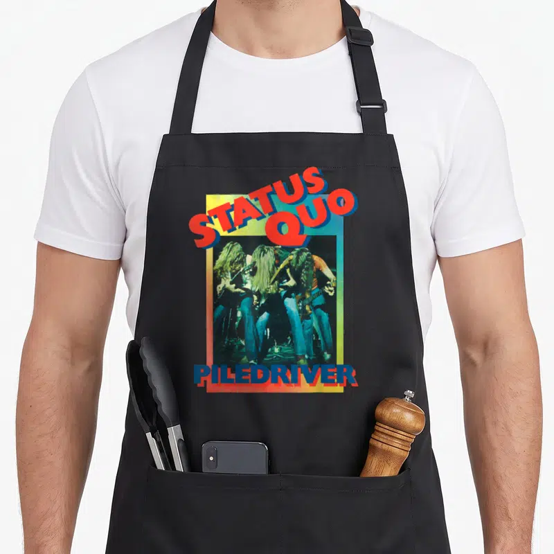 Tablier de cuisine noir avec illustration Status Quo Piledriver montrant des guitaristes aux longs cheveux sous un cadre multicolore.