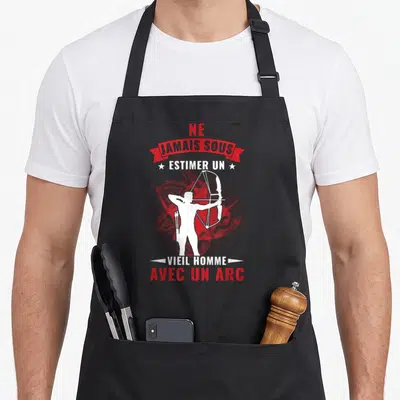 Tablier de cuisine noir avec silhouette blanche d'archer et texte Ne jamais sous estimer un vieil homme avec un arc sur fond rouge texturé.