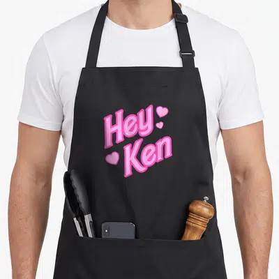 Tablier de cuisine noir avec inscription Hey Ken en rose et cœurs brillants.