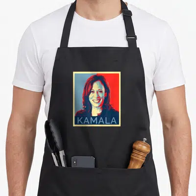 Tablier de cuisine noir avec portrait Kamala Harris en pop art rouge et bleu et le texte KAMALA en bas.