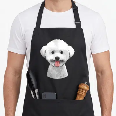 Tablier de cuisine noir avec illustration d'un Bichon Frise blanc au sourire joyeux et langue sortie.