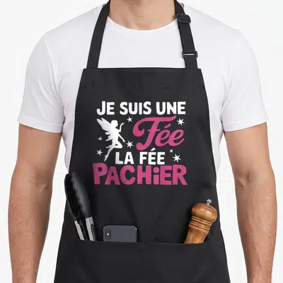 Tablier de cuisine noir avec inscription Je suis une fée la fée Pachier en rose et blanc accompagnée d'une silhouette d'ange et d'étoiles.