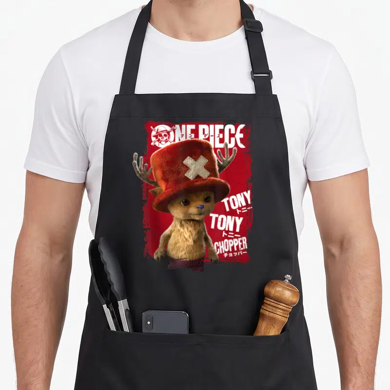 Tablier de cuisine noir avec Tony Tony Chopper, chapeau rouge à croix et texte blanc sur fond rouge texturé.