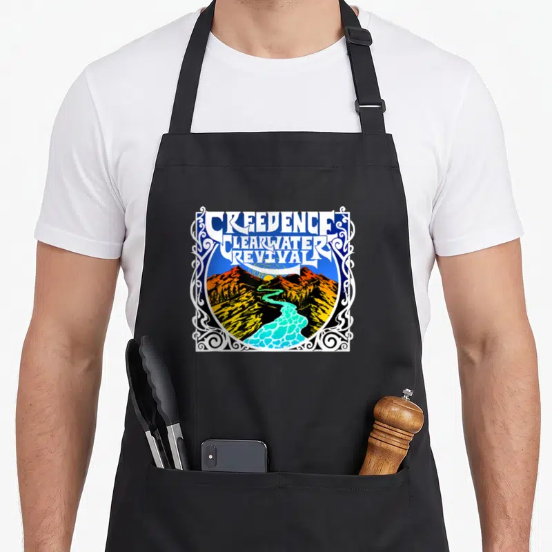 Tablier de cuisine noir avec une illustration colorée représentant une rivière et des montagnes sous un logo stylisé blanc et bleu.