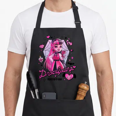 Tablier de cuisine noir avec illustration colorée de Draculaura tenant un cœur rose orné d'ailes de chauve-souris.