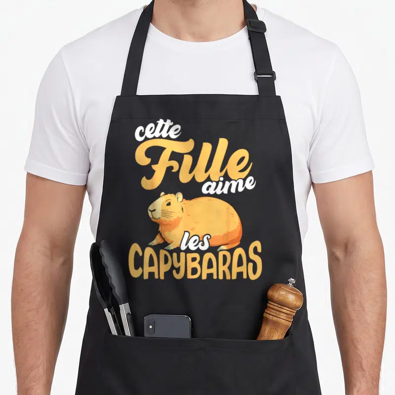 Tablier de cuisine noir avec illustration d'un capybara orange et le texte cette Fille aime les CAPYBARAS en typographie stylisée.