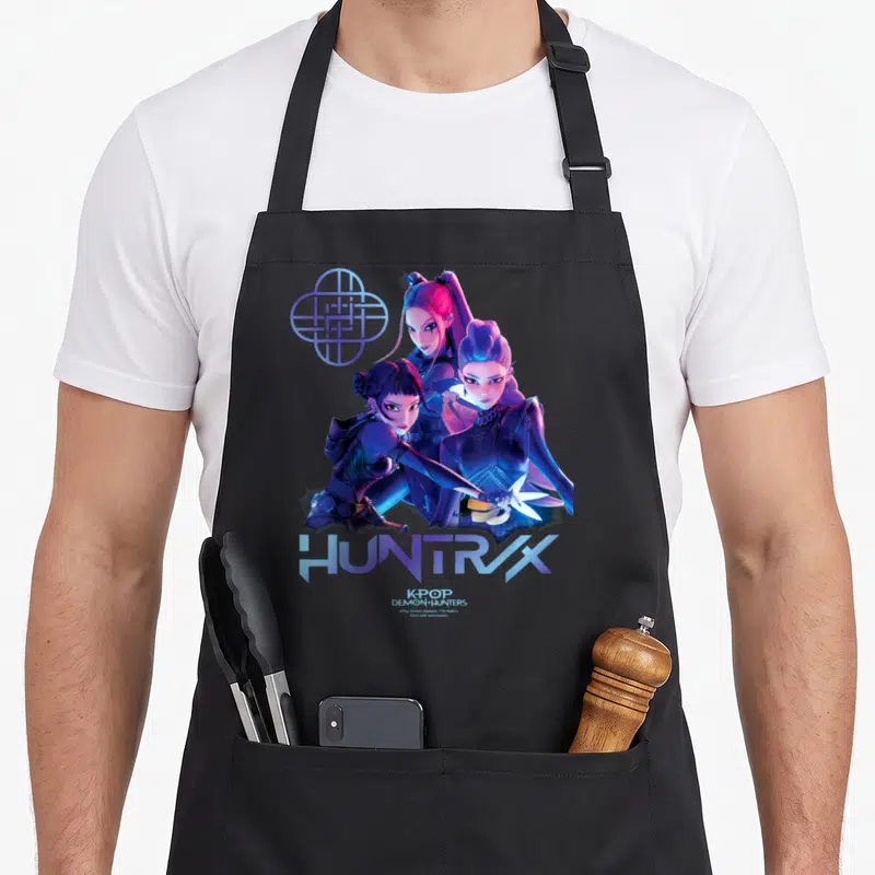 Tablier de cuisine noir avec illustration des Huntrix et leur logo géométrique bleu néon.