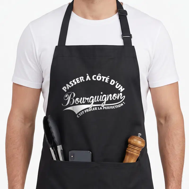 Tablier de cuisine noir avec l'inscription blanche Passer à côté d'un Bourguignon c'est frôler la perfection en typographie stylisée.