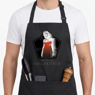 Tablier de cuisine noir avec portrait femme robe rouge logo pentagone et texte Battlestar Galactica