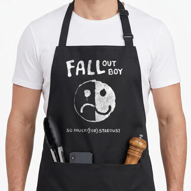 Tablier de cuisine noir avec le texte Fall Out Boy, un visage souriant et triste, et So Much For Stardust imprimé en blanc.