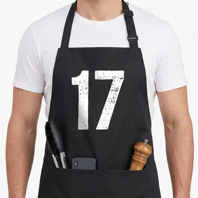 Tablier de cuisine noir avec le chiffre 17 en blanc texturé au centre du vêtement.