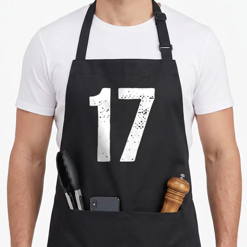 Tablier de cuisine noir avec le chiffre 17 en blanc texturé au centre du vêtement.