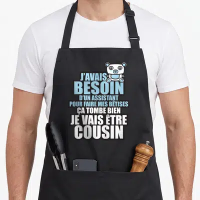Tablier de cuisine noir avec texte bleu et blanc et petit ours blanc en haut à droite.