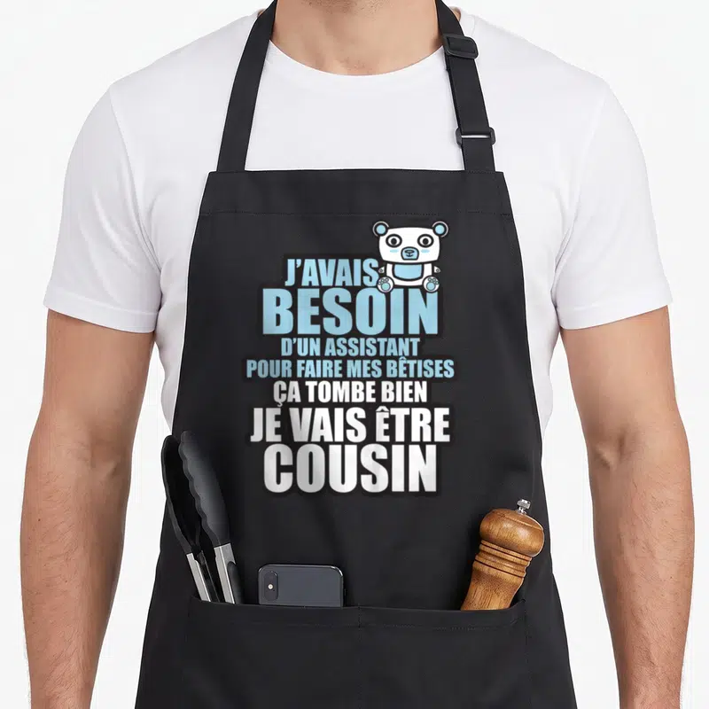 Tablier de cuisine noir avec texte bleu et blanc et petit ours blanc en haut à droite.