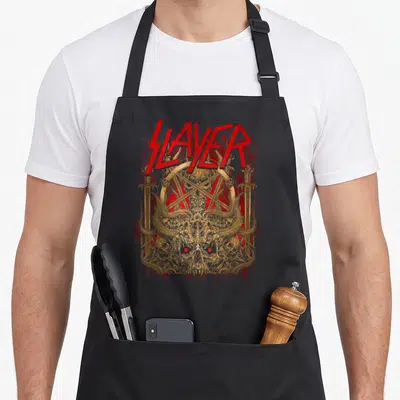 Tablier de cuisine noir avec logo Slayer rouge et illustration dorée de crâne démoniaque orné d'épées.