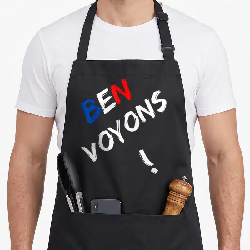 Tablier de cuisine noir avec l'expression BEN VOYONS. en typographie brossée tricolore.