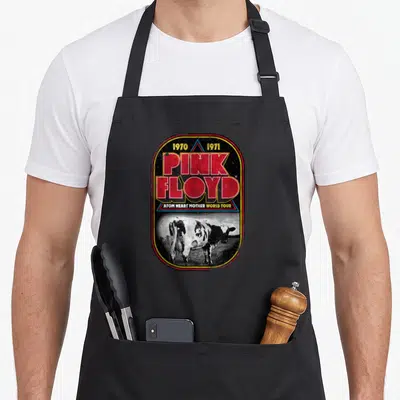 Tablier de cuisine noir avec un motif rectangulaire vintage affichant le texte Pink Floyd et une illustration de vache en noir et blanc.