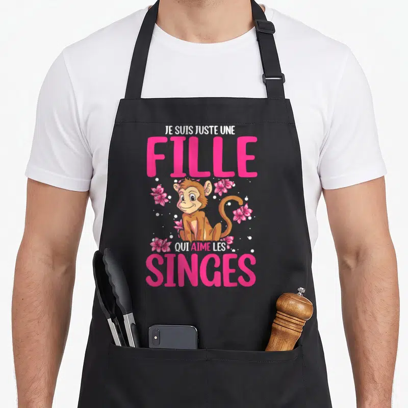 Tablier de cuisine noir avec illustration de singe entouré de fleurs roses et texte en rose vif.