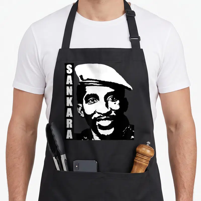 Tablier de cuisine noir avec portrait stylisé de Thomas Sankara et texte vertical SANKARA sur le côté gauche.