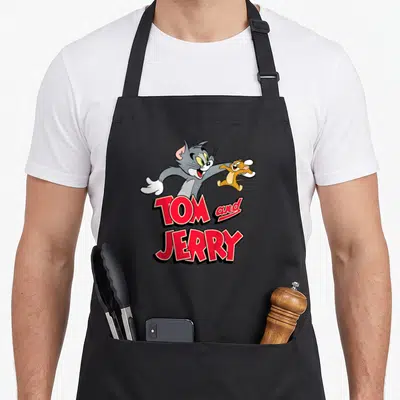 Tablier de cuisine noir avec illustration de Tom et Jerry souriants et du texteTom and Jerry en lettres rouges.
