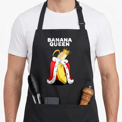 Tablier de cuisine noir avec illustration d'une banane royale portant une couronne et une cape rouge.