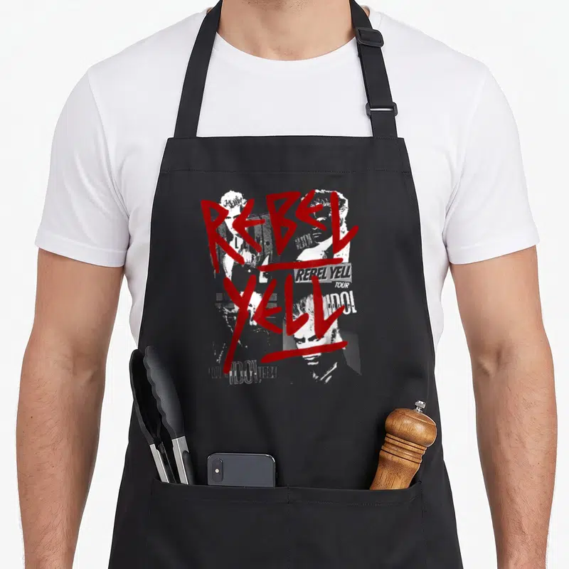 Tablier de cuisine noir avec inscription Rebel Yell en rouge et visages de Billy Idol en blanc et gris.