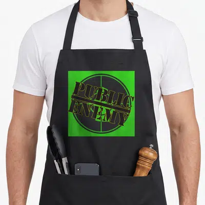 Tablier de cuisine noir avec le logo vert Public Enemy sur fond de cible grise.