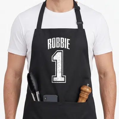 Tablier de cuisine noir avec l inscription Robbie et un grand chiffre 1 en blanc au style dégradé.