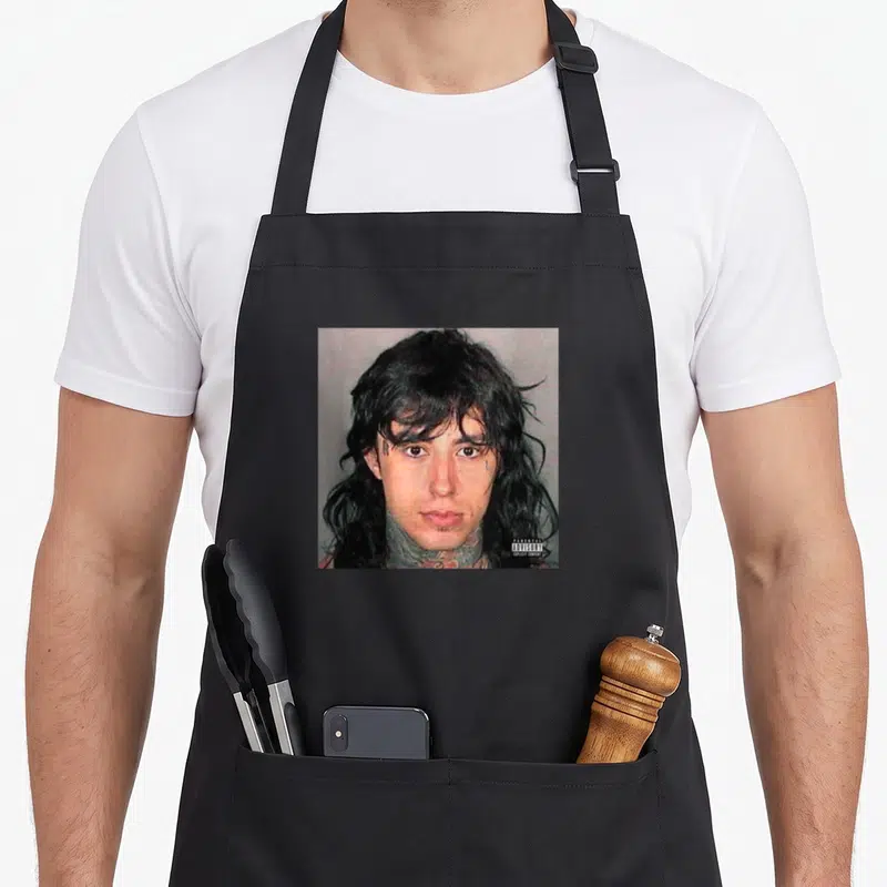 Tablier de cuisine noir avec portrait du Monstre populaire et étiquette Parental Advisory Explicit Content en bas à droite.