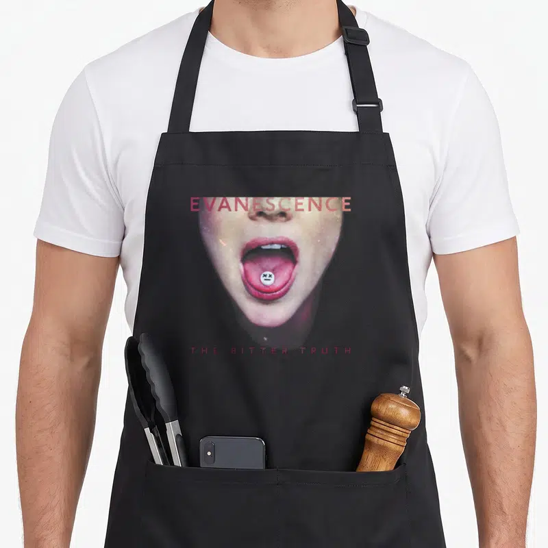Tablier de cuisine noir avec une illustration faciale aux lèvres roses et un bouton blanc sur la langue.