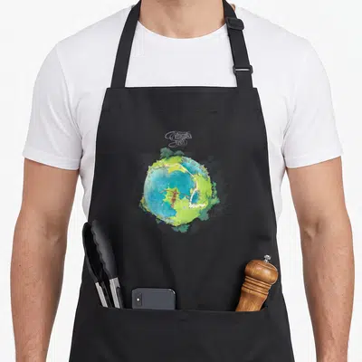Tablier de cuisine noir avec illustration colorée d'un petit monde rond et du texte Oui Fragile en haut.