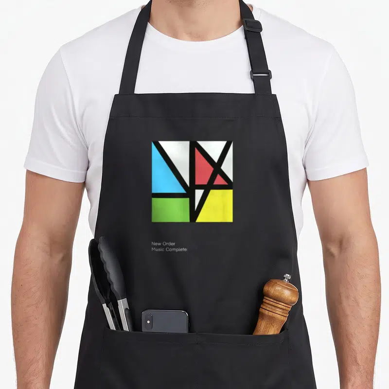 Tablier de cuisine noir avec une composition géométrique aux formes triangulaires bleue, rouge, verte et jaune séparées par des lignes noires.