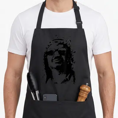 Tablier de cuisine noir avec portrait graphique de Yasser Arafat portant des lunettes et un foulard traditionnel.