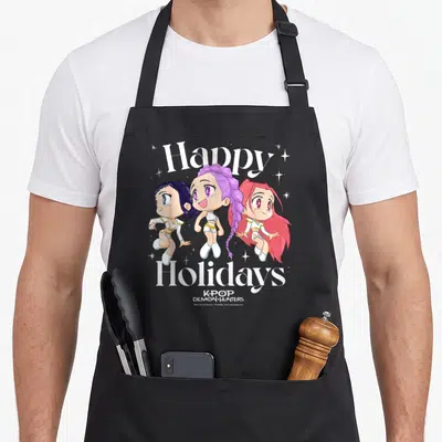 Tablier de cuisine noir avec illustration chibi Huntrix Group et texte Happy Holidays en blanc.
