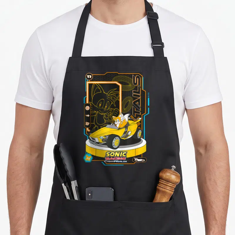 Tablier de cuisine noir avec illustration de Tails dans une kart jaune et le logo Sonic Racing CrossWorlds.