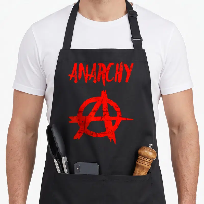 Tablier de cuisine noir avec le texte Anarchy et un symbole circulaire rouge stylisé au centre du vêtement.