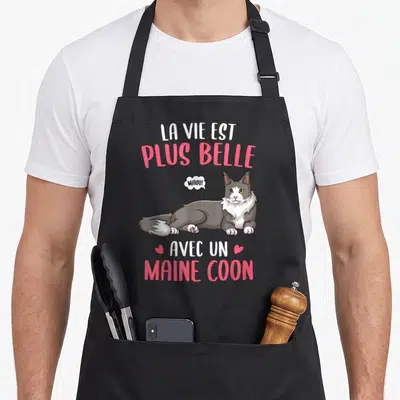 Tablier de cuisine noir avec illustration d'un Maine Coon gris et blanc et texte La vie est plus belle avec un Maine Coon en rose et blanc.