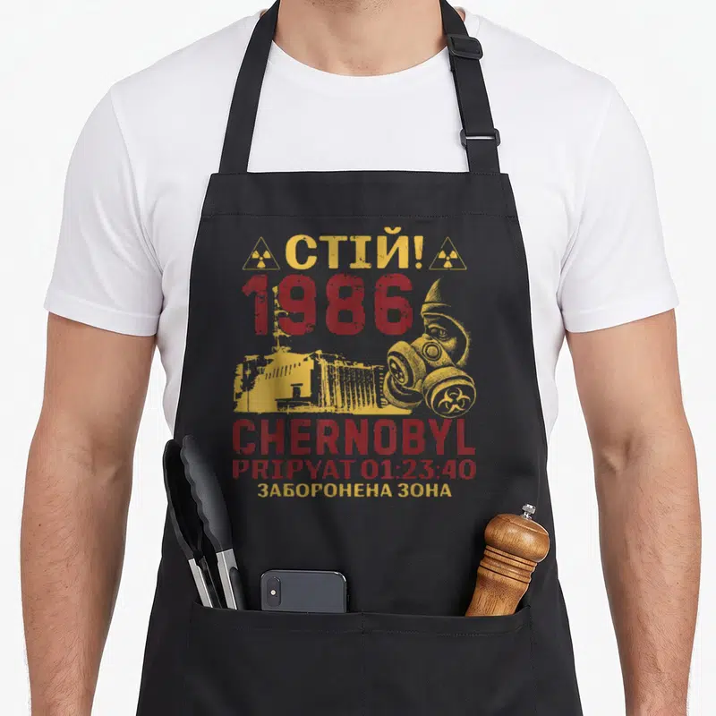 Tablier de cuisine noir avec illustration Chernobyl Pripyat 1986 et masque à gaz jaune et rouge.