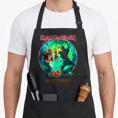 Tablier de cuisine noir avec illustration circulaire Iron Maiden Legacy of the Beast World Tour 2022 en couleurs vives.