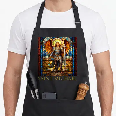 Tablier de cuisine noir avec illustration vitrail Saint Michael Archange tenant une épée et portant une armure dorée.