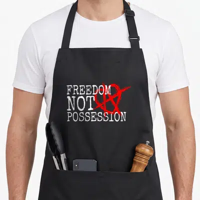 Tablier de cuisine noir avec le texte blanc Freedom Not Possition barré d'un symbole anarche rouge.