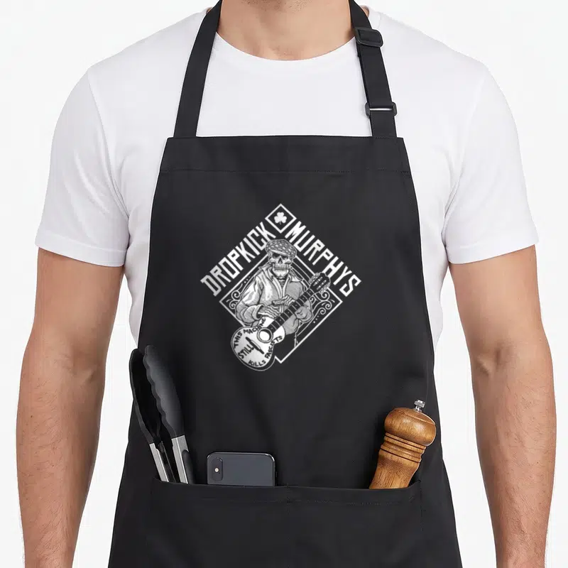 Tablier de cuisine noir avec le logo blanc du Cousin Skelly de Dropkick Murphys jouant d'un instrument.