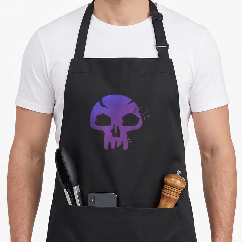 Tablier de cuisine noir avec un crâne violet stylisé aux contours érodés et des éclats dispersés sur le côté droit.