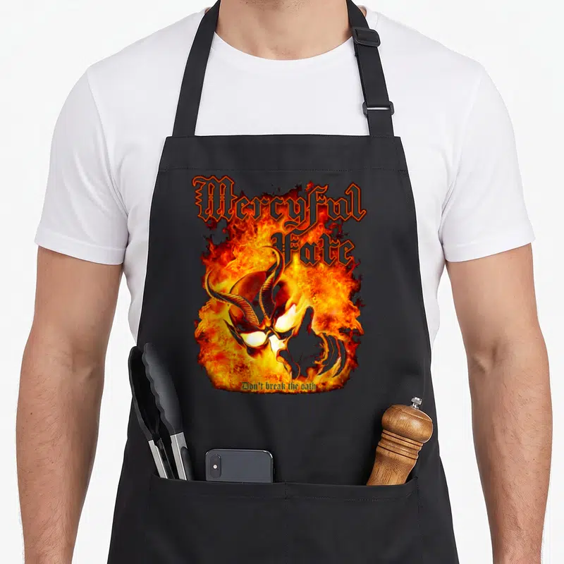 Tablier de cuisine noir avec un crâne cornu enflammé et l'inscription Mercyful Fate Don't break the oath.