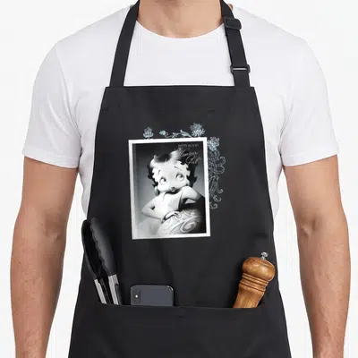 Tablier de cuisine noir avec illustration vintage de Betty Boop et texte Humour Girl en typographie cursive.